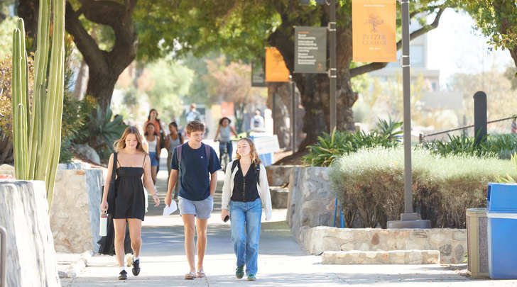 several students walk towards pitzer's gate