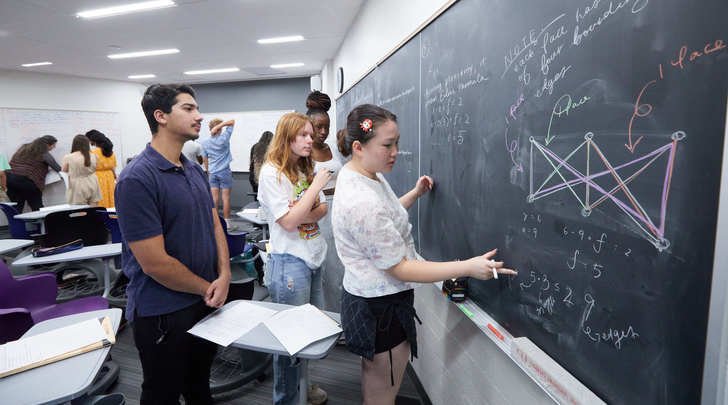 students solve math problems on a chalkboard