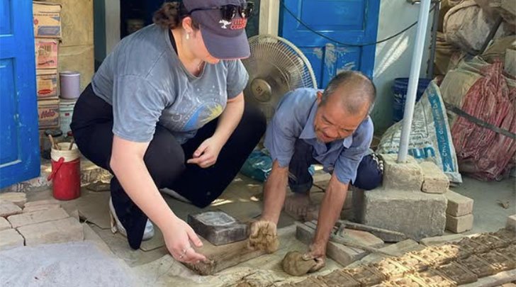 a student helps a ceramicist lay out tiles in vietnam