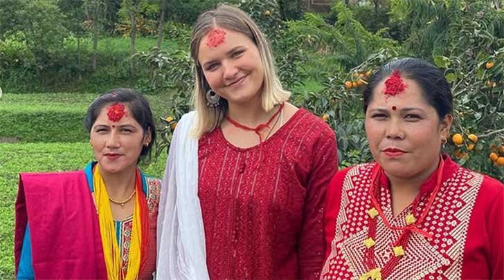 a student poses with two hosts in nepal
