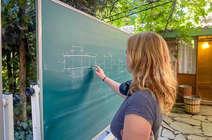 student solves math problem on an outdoor blackboard