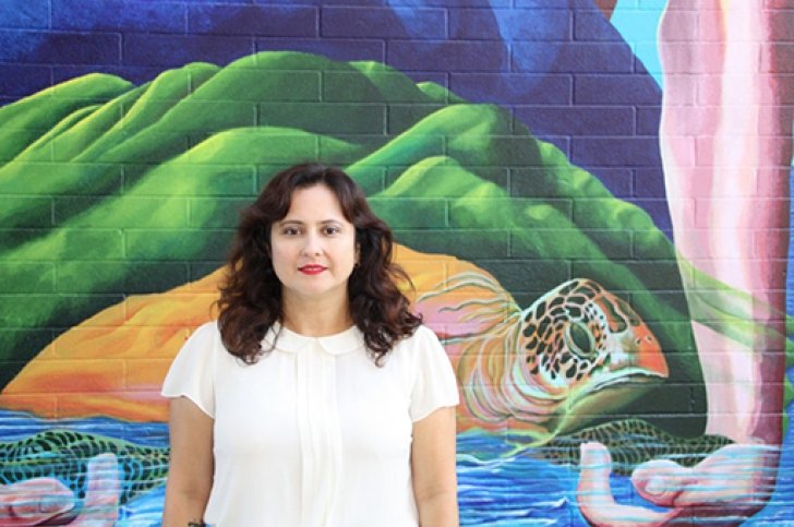 A photo of Suyapa Portillo Villeda standing in front of a mural