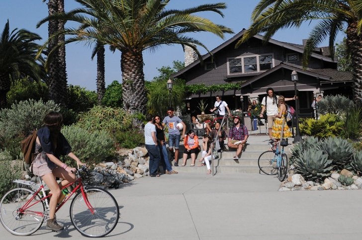 an exterior shot of the grove house with several students hanging out on the steps in front