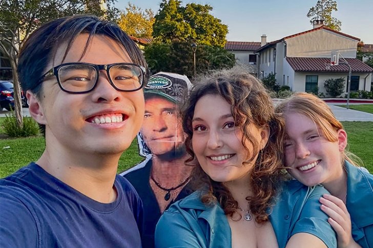 Students George Zhang, Annie Voss, and Annie Wion pose with a cardboard cutout of Survivor TV host Jeff Probst in the middle.