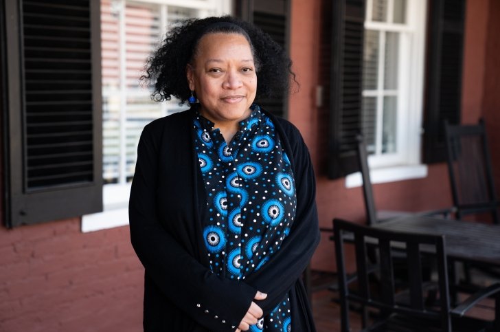 Dean of Faculty Chawne Kimber stands on front porch and wears a black sweater and blue scarf
