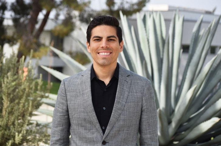 Marcus Rodriguez has short black hair and wears a gray blazer over a black shirt.