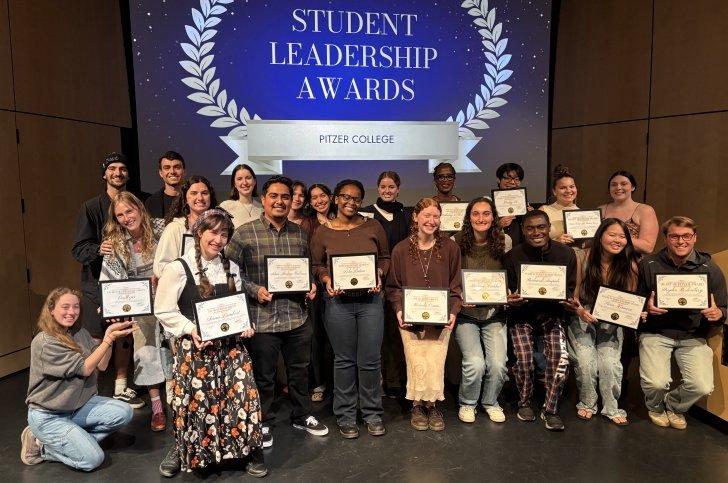 Group photo of student award winners on Benson stage underneath a blue awards banner