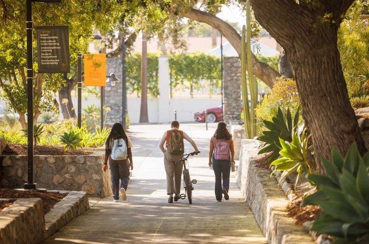 three students walk down pitzer walk toward pitzer gate