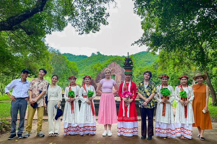 Pitzer students pose with women in traditional Vietnamese dresses