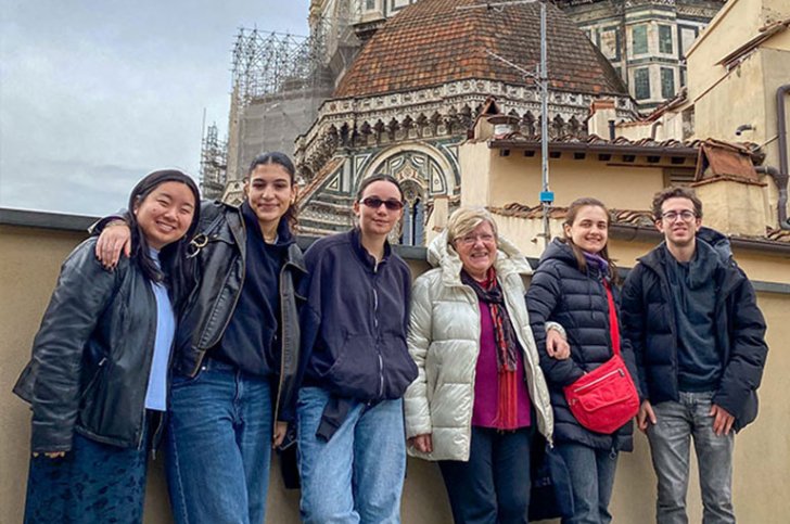 students pose with pitzer in italy director at a historic site