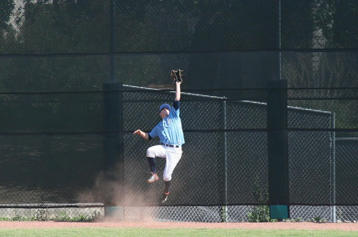 a baseball player jumps to catch a ball in the outfield
