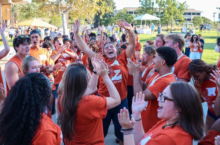 a group of students in orange shirts cheering