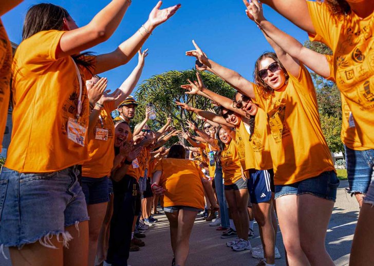 a new student walks down a welcome path of student affair greeters