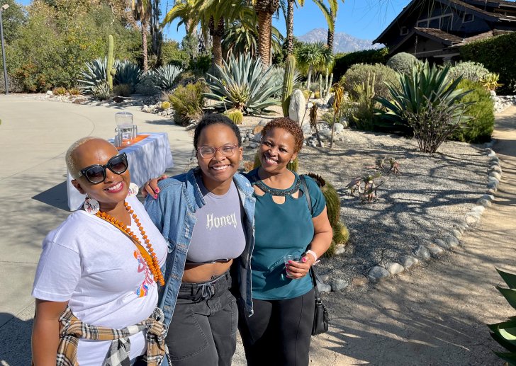 Three women posing in front of Grove House in 2022.