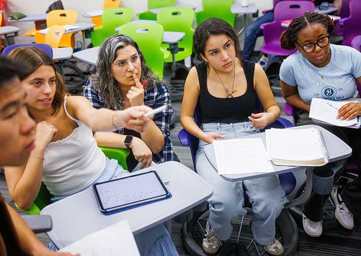 students sit in a desk and point at something off in the distance