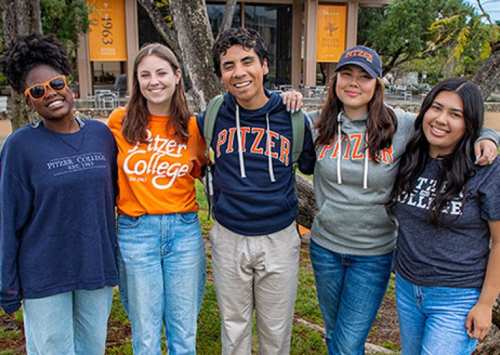 five students wearing pitzer shirts and sweaters stand in front of mcconnell apron
