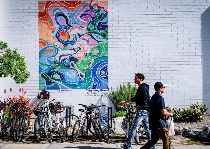 two student walk past a colorful abstract mural