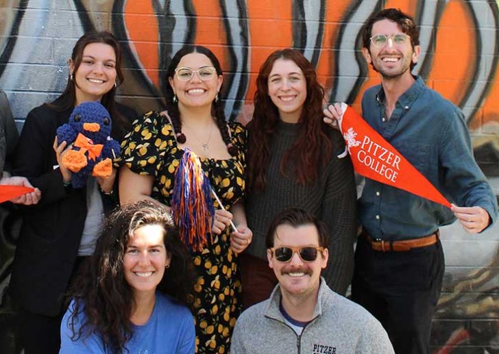 admission counselors hold up orange pitzer pennants