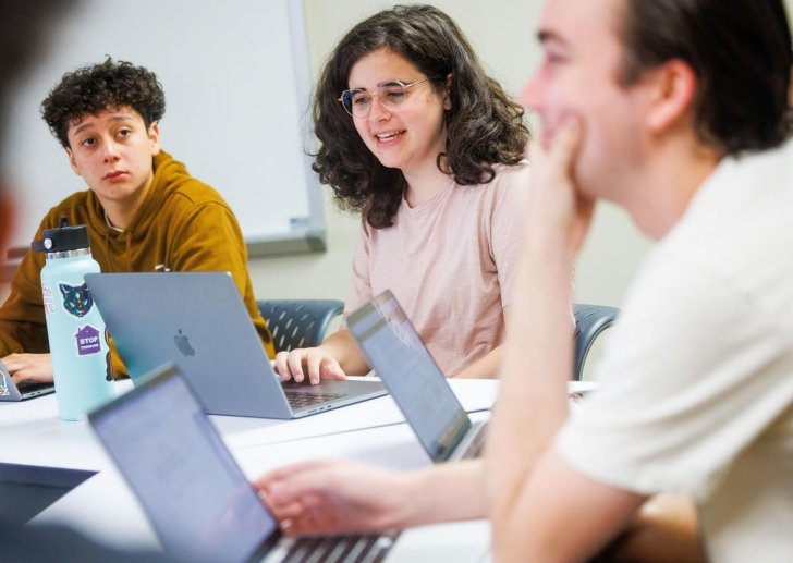 students discuss at desks in a classroom