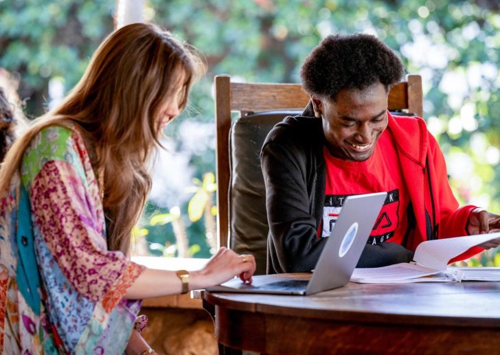 two students sit at a table on the porch of the grove house
