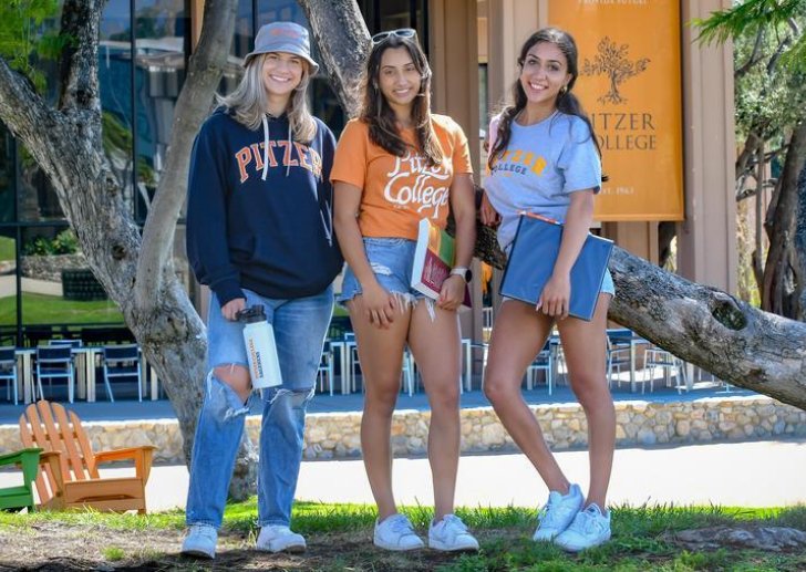 three students stand in front of McConnell Center wearing Pitzer merch