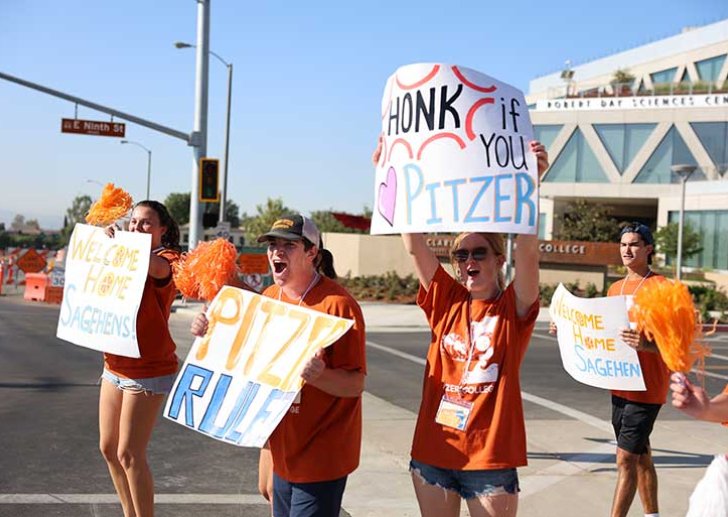 pitzer students hold up welcome signs on the corner of 9th street and claremont blvd during move-in day