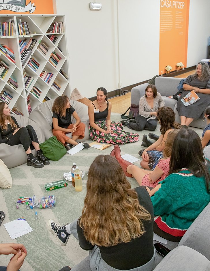 A group sits on the ground in a circle at CASA Pitzer