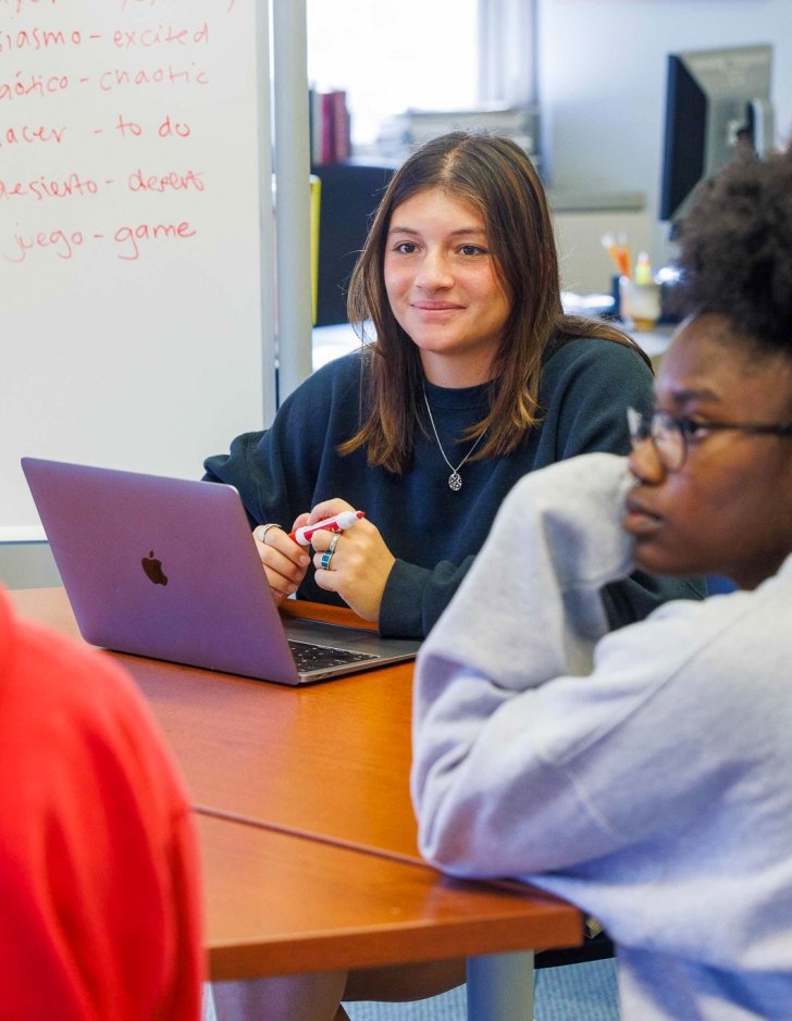 Student with laptop listens to discussion.