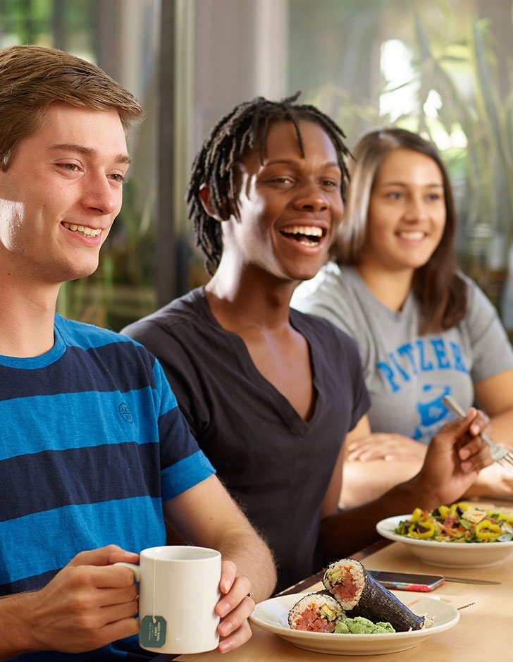 three students eat lunch in the dining hall