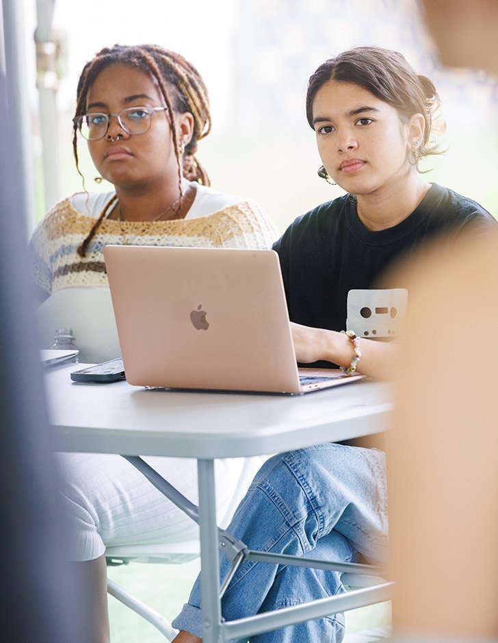 two students listen to another student speak in class