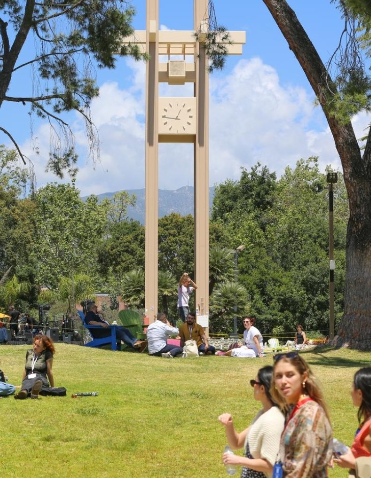 A Pitzer alum walks on a slackline in front of Brant Clock Tower
