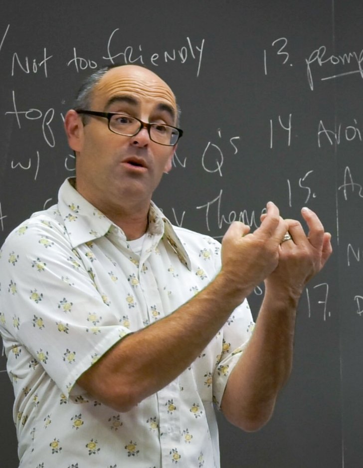 phil zuckerman lectures in a classroom while being filmed