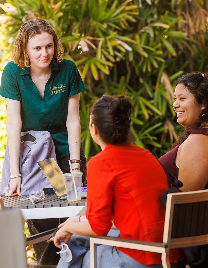 three students sit outside pit stop cafe