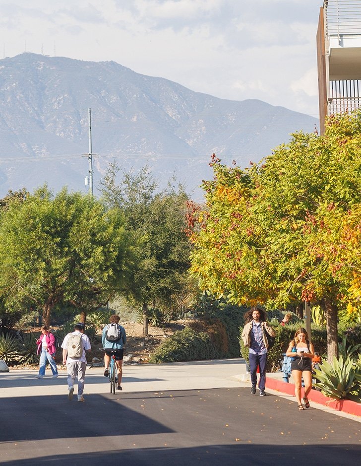 several students walk down pitzer road with the san bernardino mountains in the background