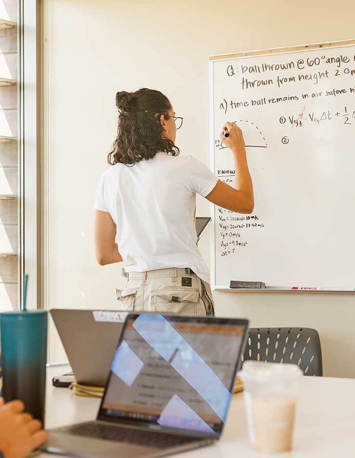 a student solves a math problem on a whiteboard