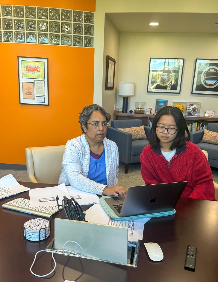 Sumangala Bhattacharya sits in front of a computer monitor with a student volunteer for a recent legal clinic