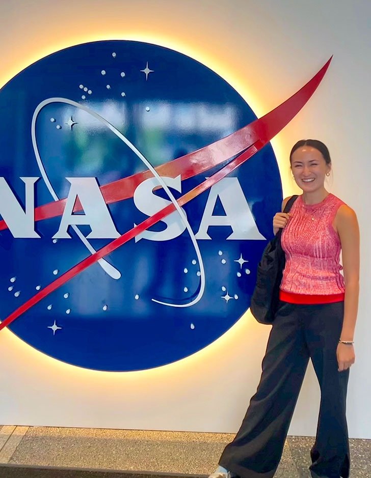 a student stands in front of a NASA sign