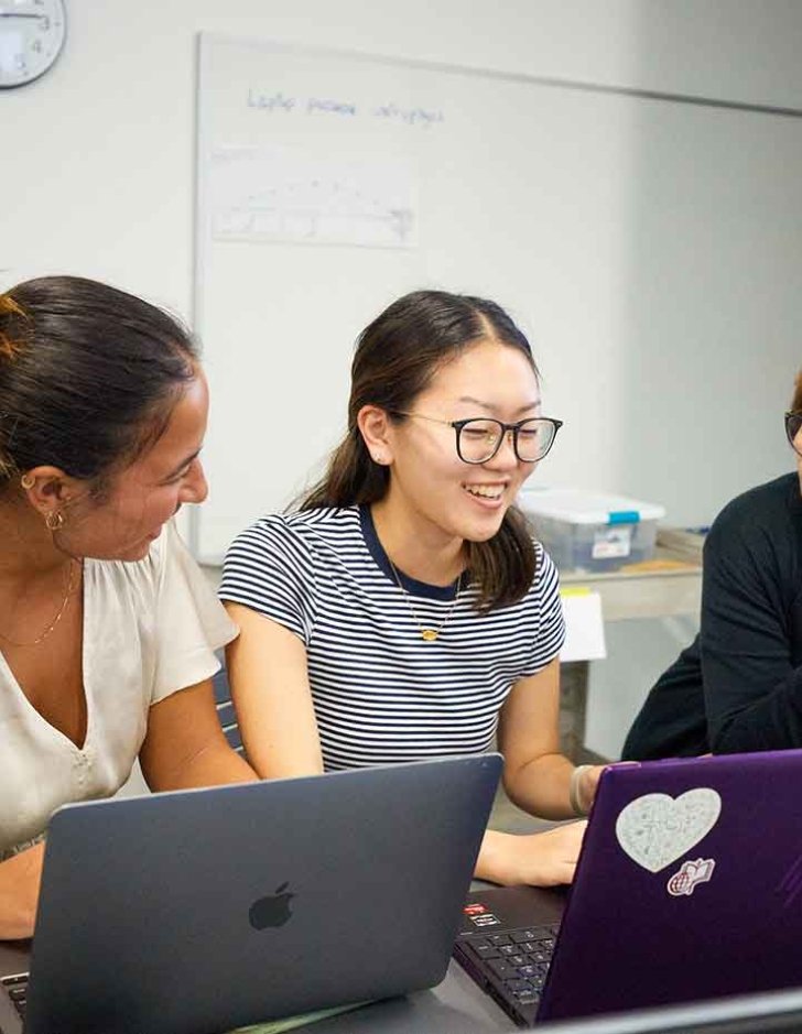 two students meet with a faculty member in a nucleus classroom