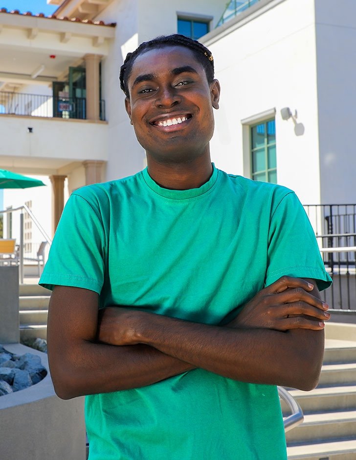 richard ampah wears a green tshirt and poses in front of the nucleus building