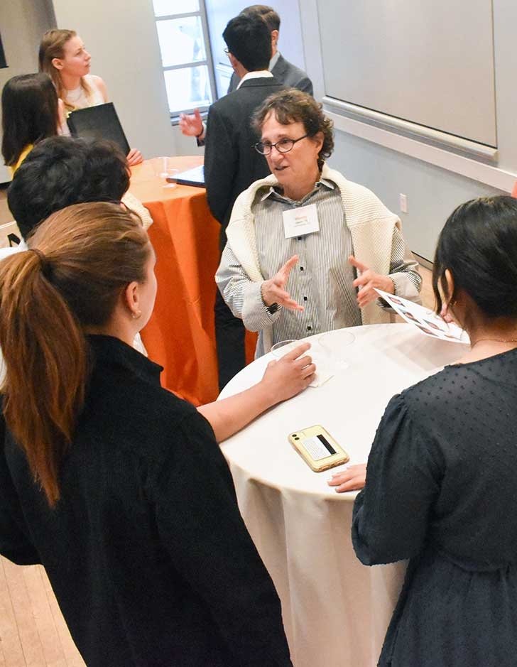 an employer chats with three students at a meet and greet