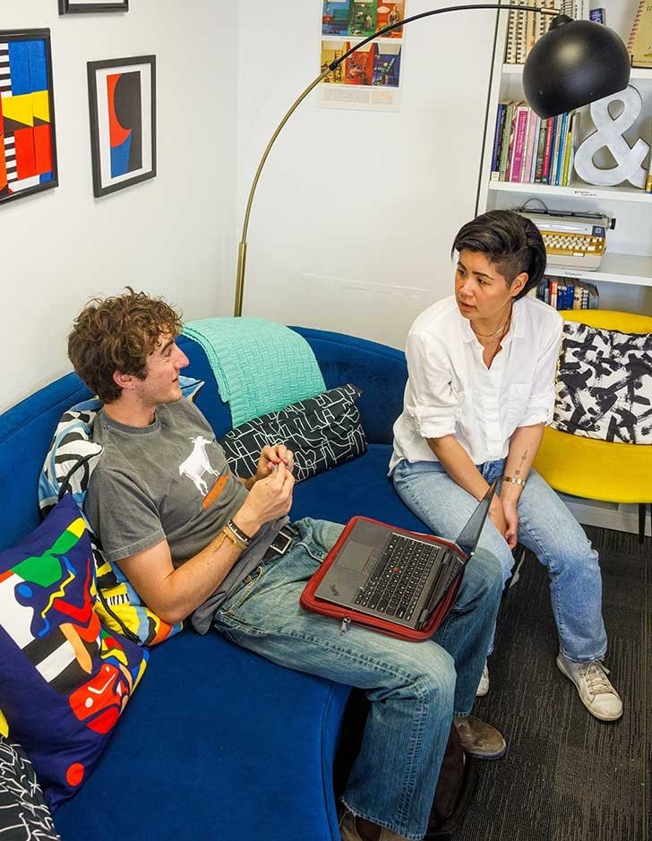 a student sits on a couch in the Writing center with one of its instructors