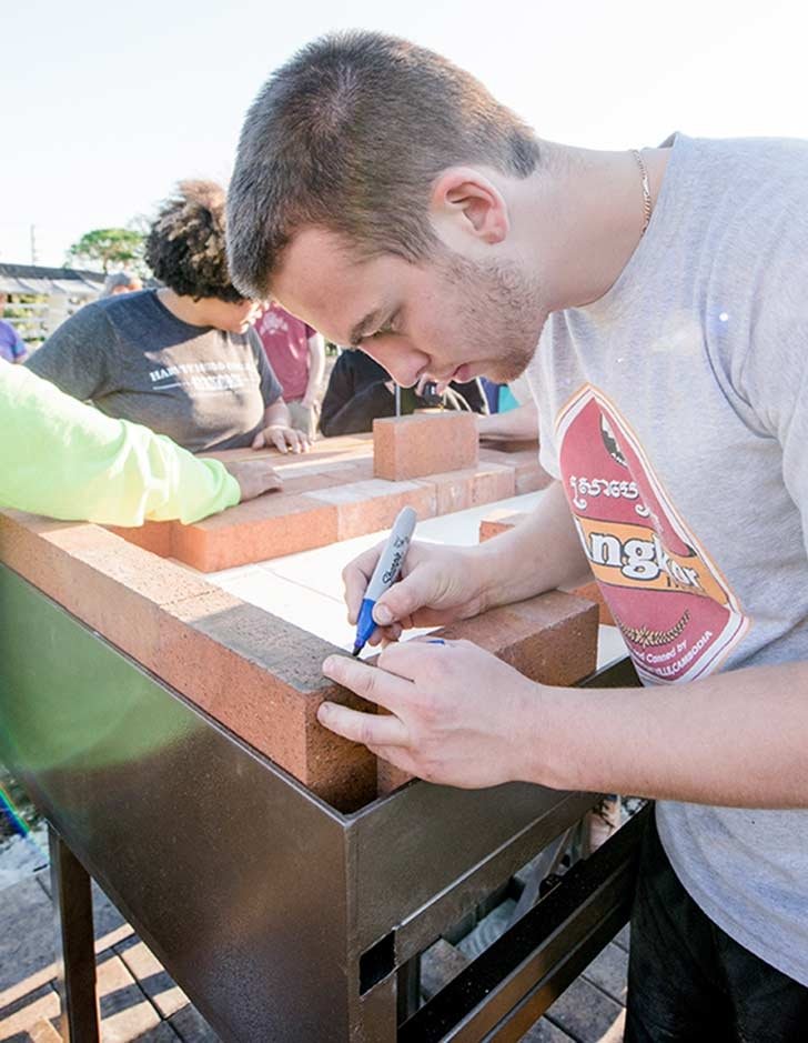 a student marks measurements on a piece of wood during a work session at huerta del valle
