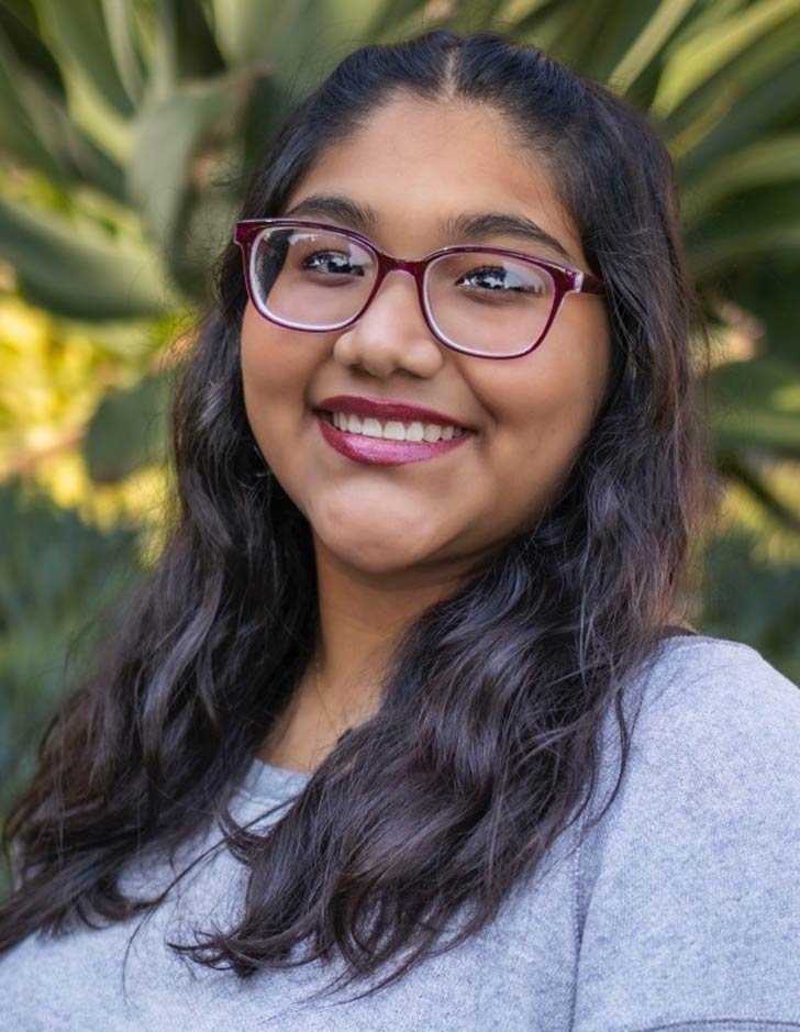 headshot of vanessa Bautista wearing burgundy glasses and a grey thermal