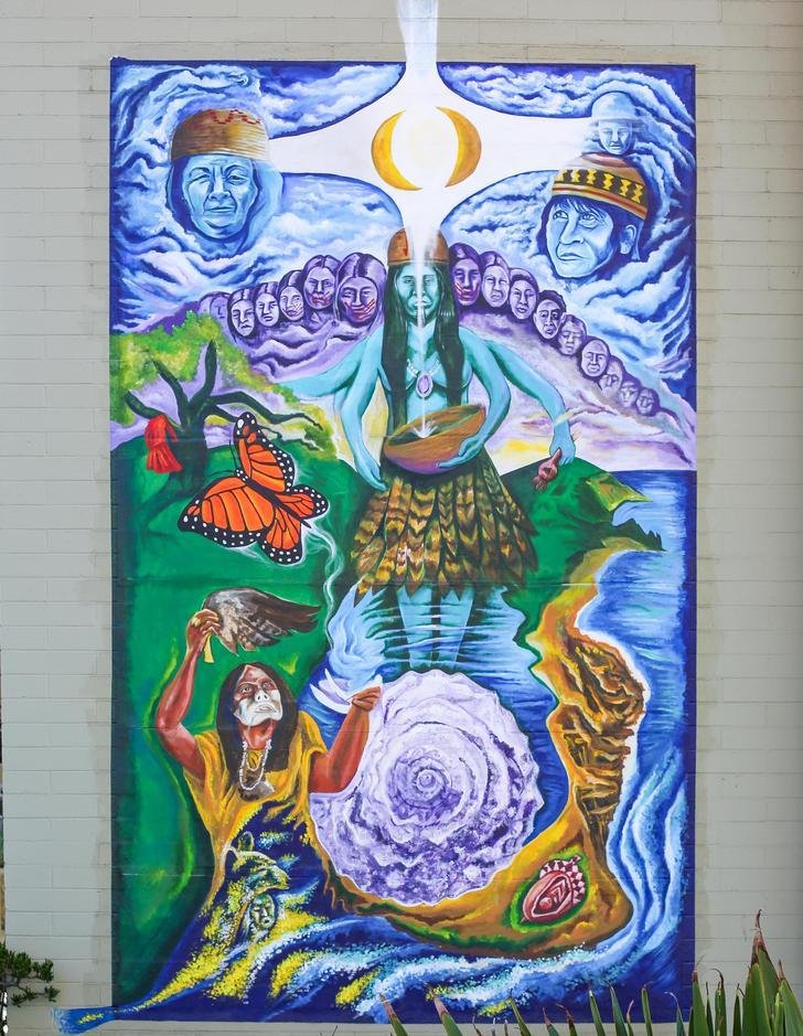 a mural showing the creation story of two sisters, with human figures circling a body of water