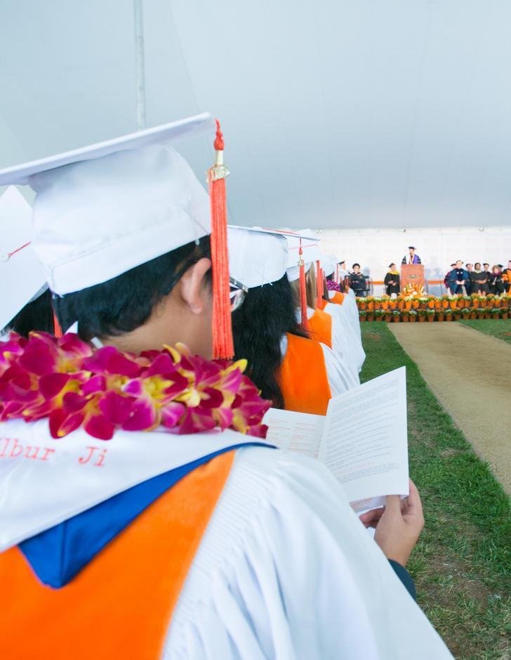 a student sitting in the commencement tent reads the schedule of events 