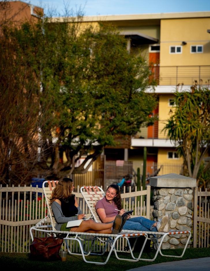 two students sit on lawn chairs outside a Pitzer dorm