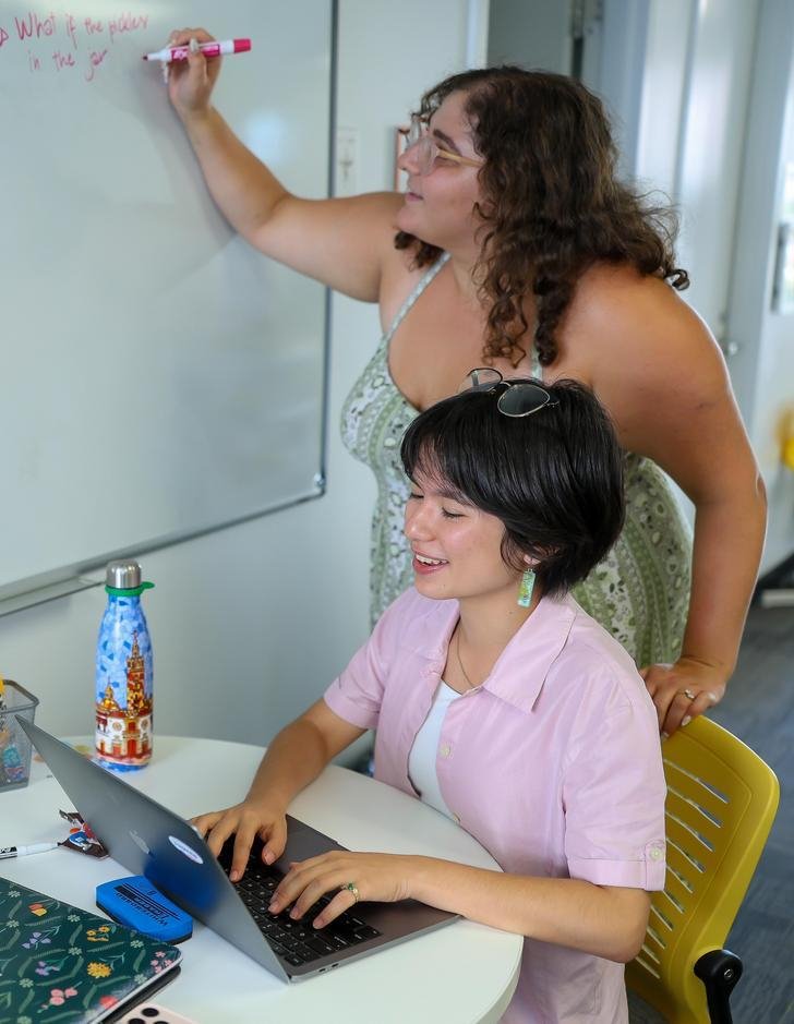 two students writing on a whiteboard