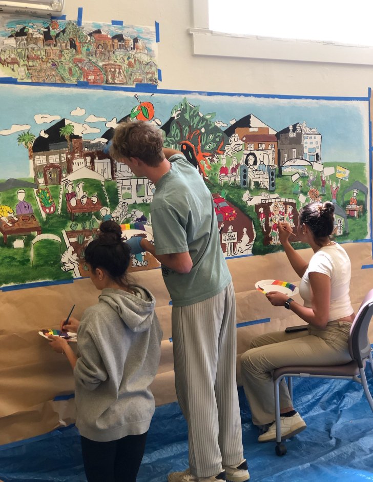 students painting a mural inside a room