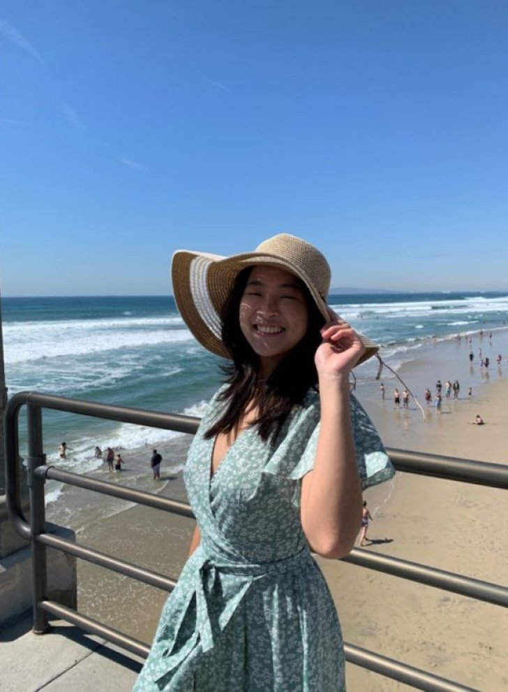 Heui Ming Lim poses on beach pier with the ocean in the background
