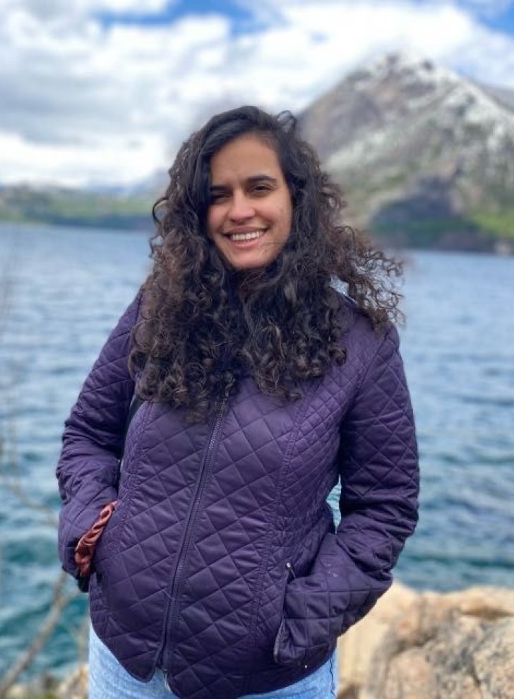 Close-up of Thais Guerra standing in front of a lake.